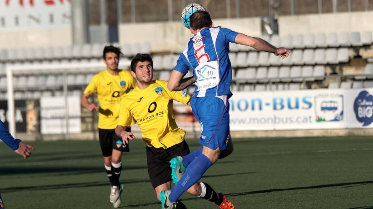 Dos jugadors del Lleida Esportiu B en pressionen un del Vilanova, que cedeix la pilota de cap.