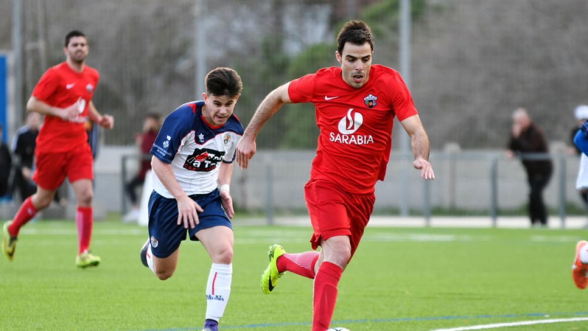 Un jugador de l’Alpicat s’escapa amb la pilota als peus davant de la persecució d’un jugador local.