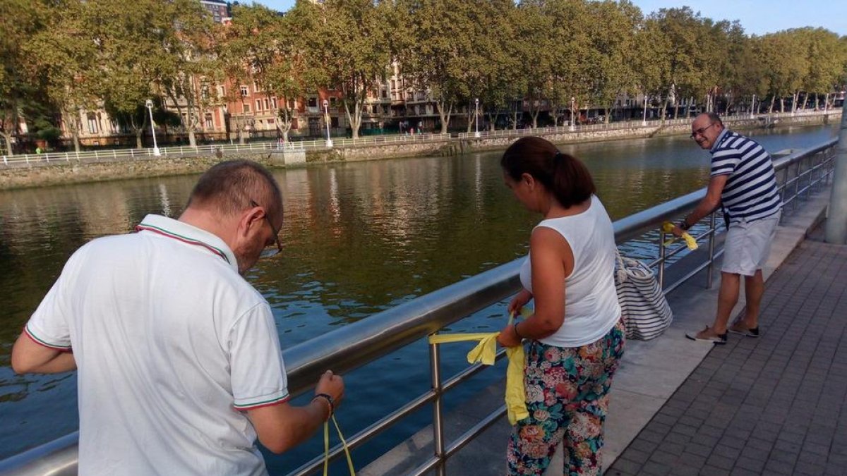 Varias personas colocan lazos amarillos en las cercanías del museo Guggenheim de Bilbao.