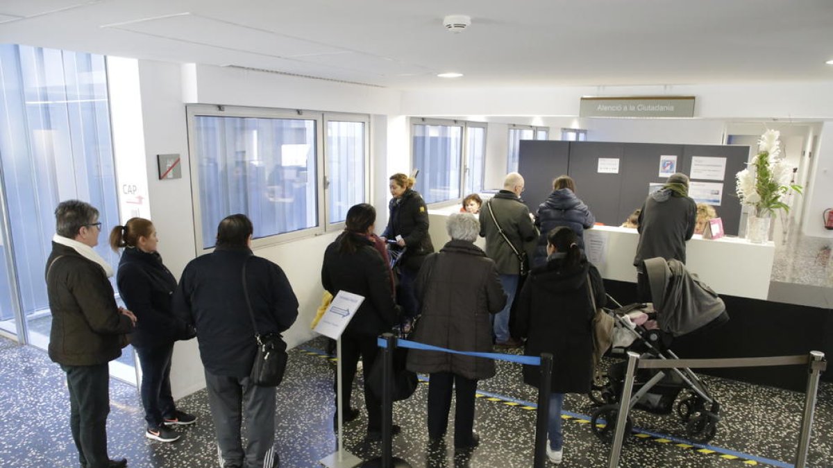 Pacients esperant davant del taulell de programació de visites en un CAP.