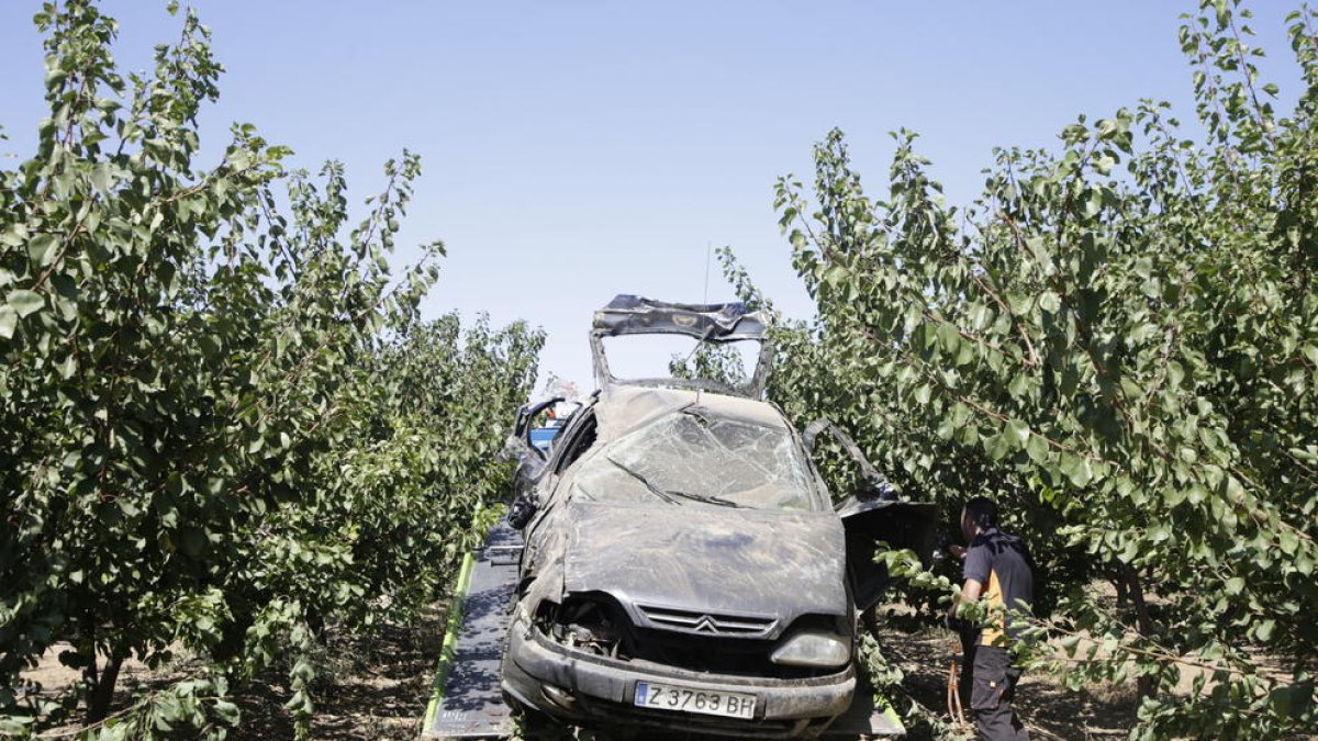 Momento en el que la grúa retira el coche accidentrado entre los árboles frutales.
