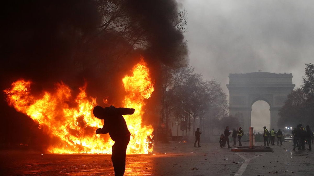 Un grup d’‘armilles grogues’ (‘gilets jaunes’) s’enfronten a la policia antiavalots prop de l’Arc de Triomf a París.
