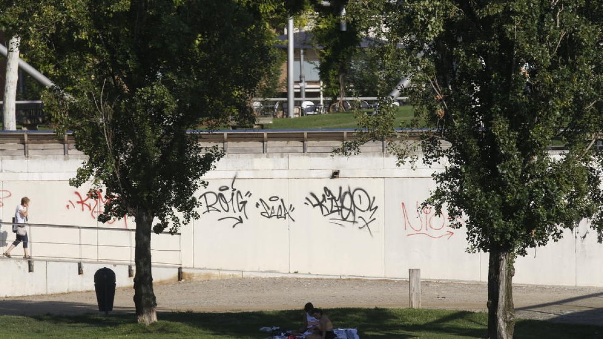 Dos joves es protegien ahir de la calor a l’ombra dels arbres a prop del riu Segre.