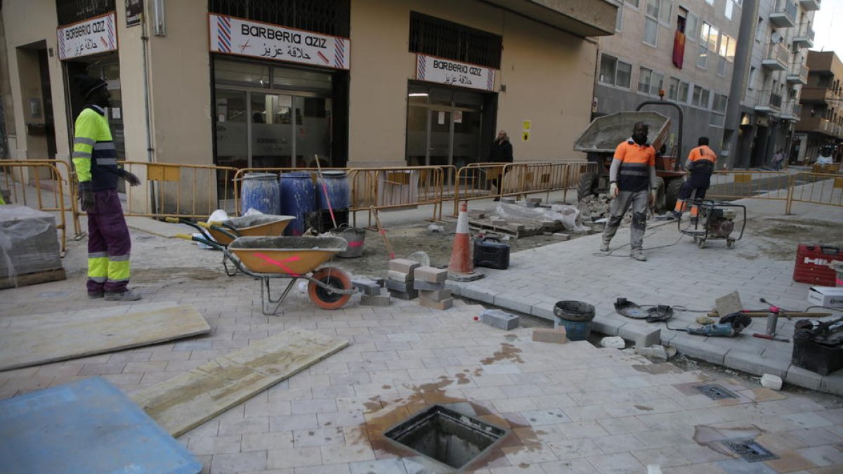 Operarios poniendo las nuevas baldosas de la calle Maria Sauret, ayer.