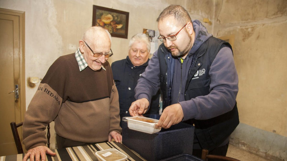 Miquel Àngel y Francisca de Alba entregando la comida a Josep de 86 años y que vive solo.