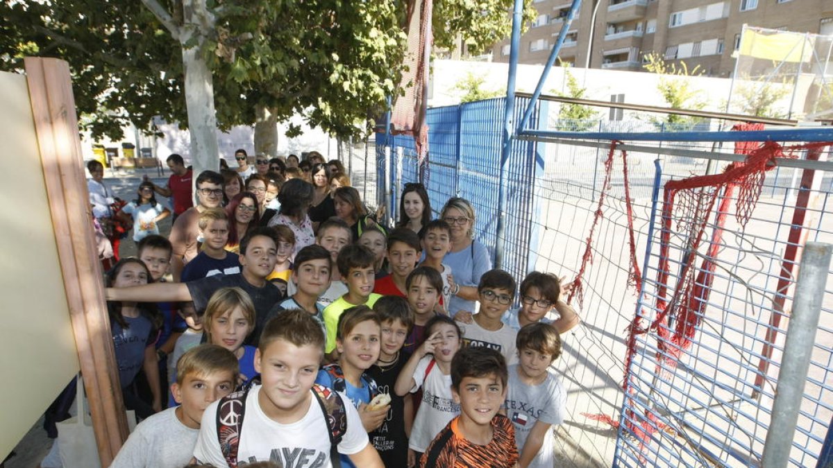 Pares i alumnes del Tonucci, al costat de la pista poliesportiva precintada.