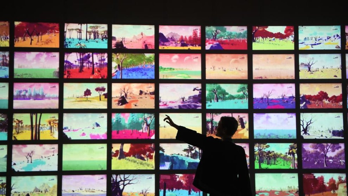 Una joven interactúa con unas pantallas durante la presentación a la prensa de la exposición