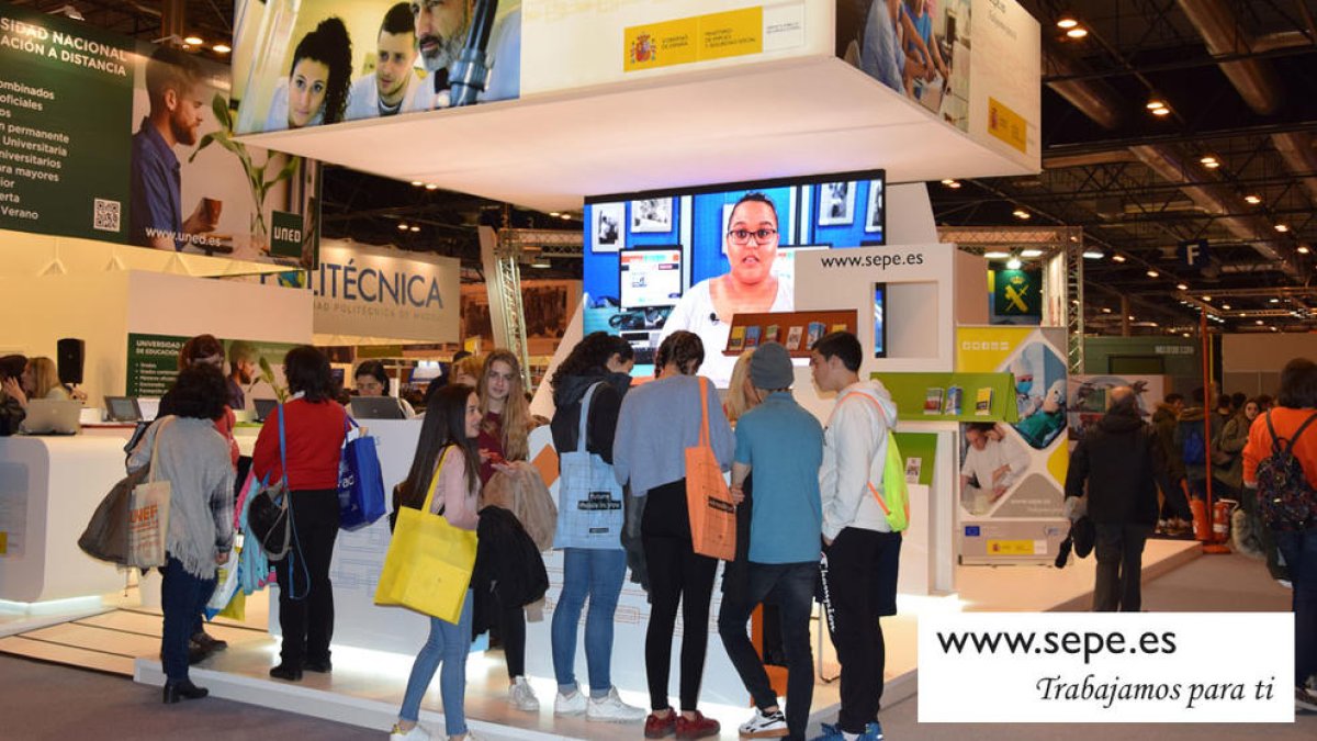 Jóvenes informándose en el puesto del Servicio Público Estatal de Empleo en una feria en Madrid.
