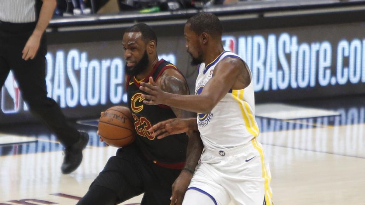 James protege la bola ante Durant, que lideró a los Warriors.