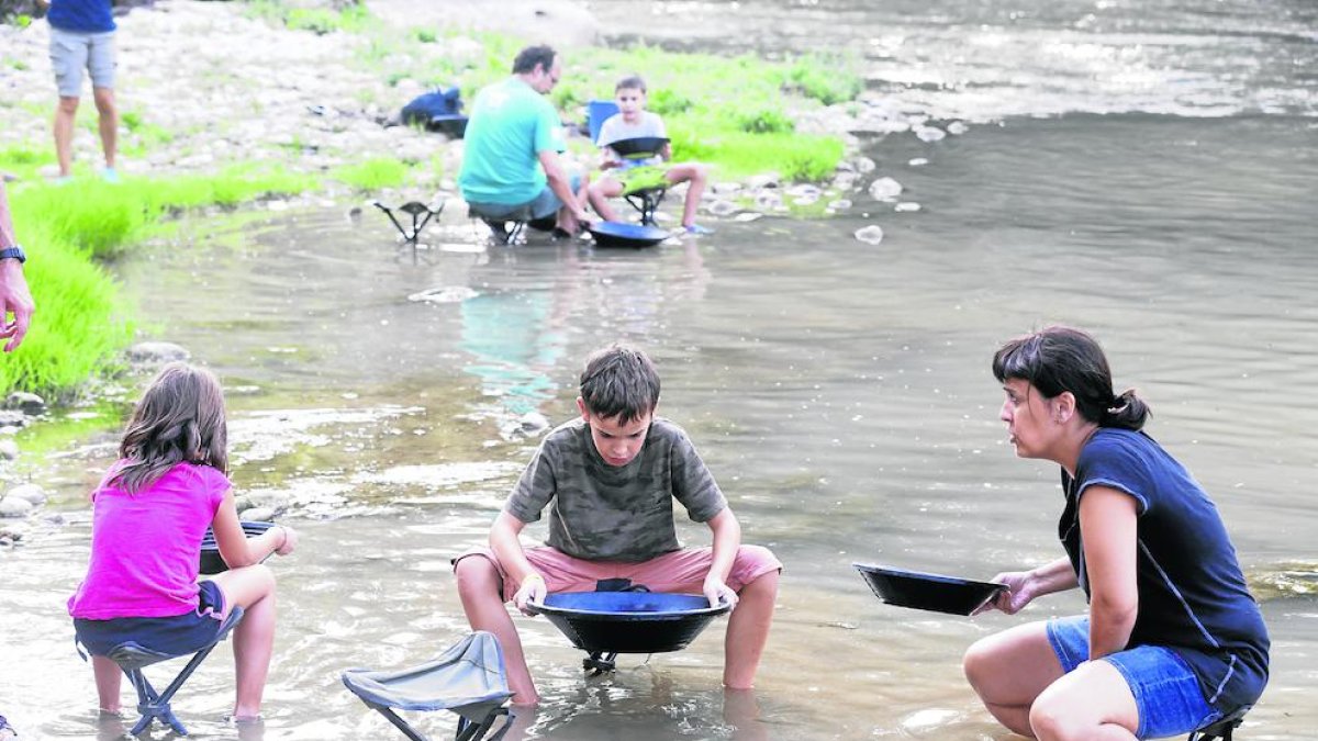 Petits i grans busquen palletes d’or al riu mitjançant l’antic procés de tamisat.