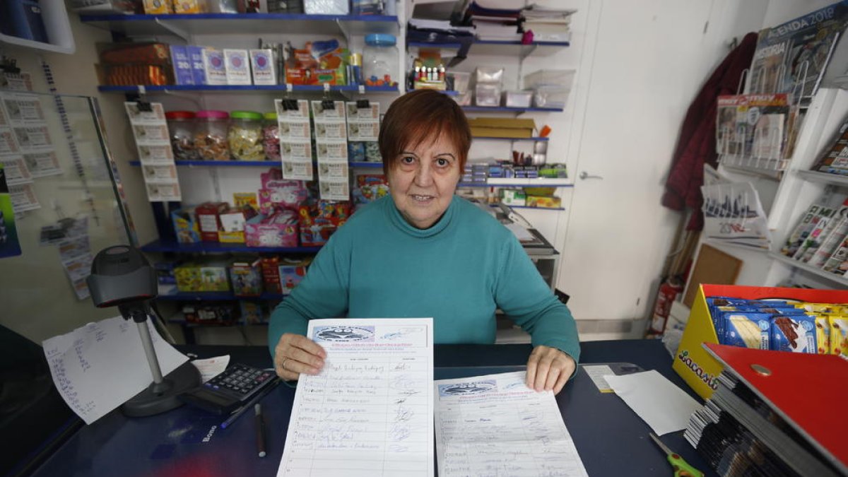 Una comerciant mostra els fulls per firmar per la iniciativa.
