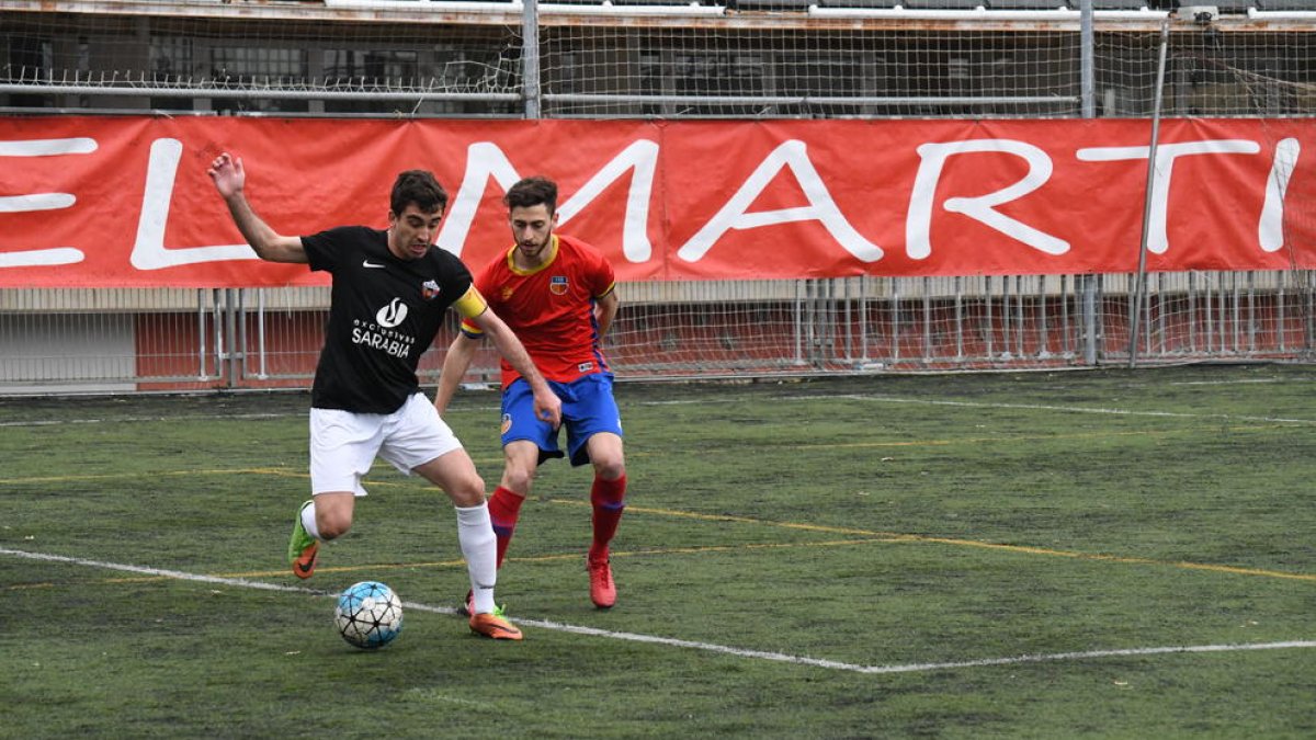El capitán del Alpicat controla el balón ante la presión de un jugador del Martinenc.