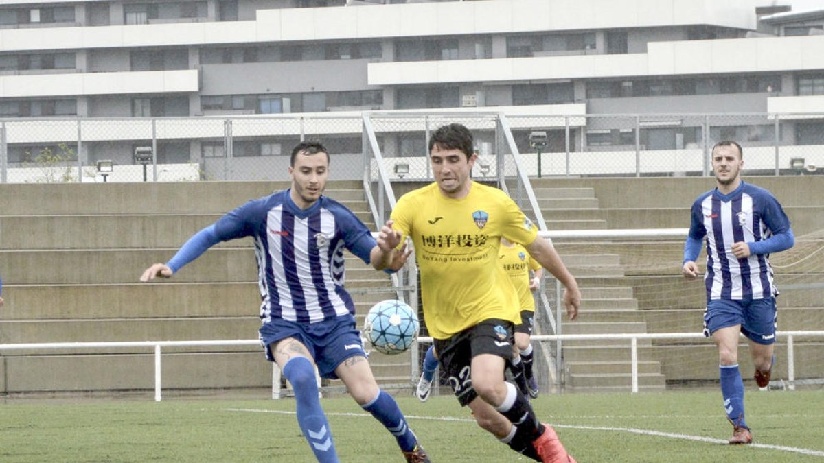 Un jugador del Lleida B con el balón controlado intenta irse por velocidad de un contrario.