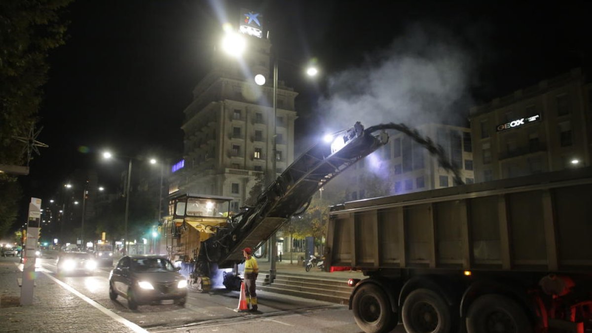 Una máquina retira el asfalto de avenida de Madrid mientras pasan dos vehículos por el carril abierto aún al tráfico, ayer por la noche.