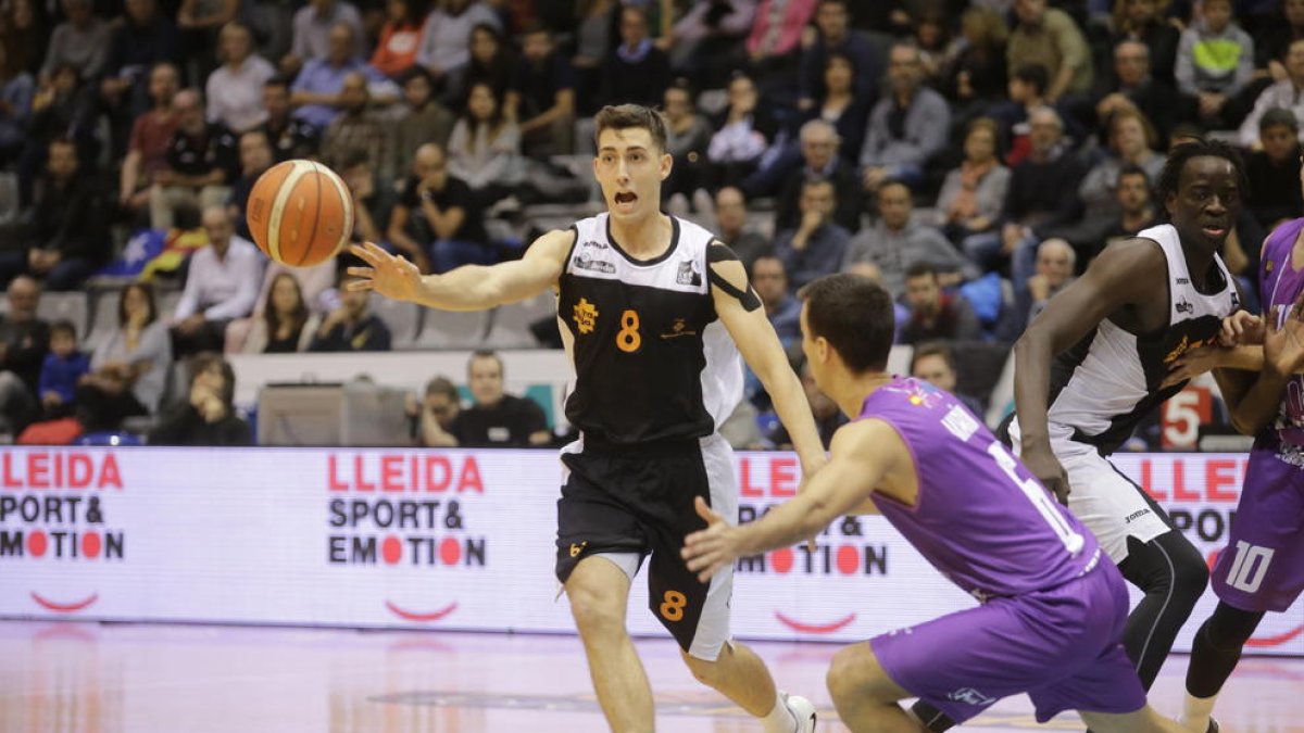 Adrián Chapela, un dels jugadors més destacats del Força Lleida, passa la pilota a un company davant la pressió de Javier Marín.