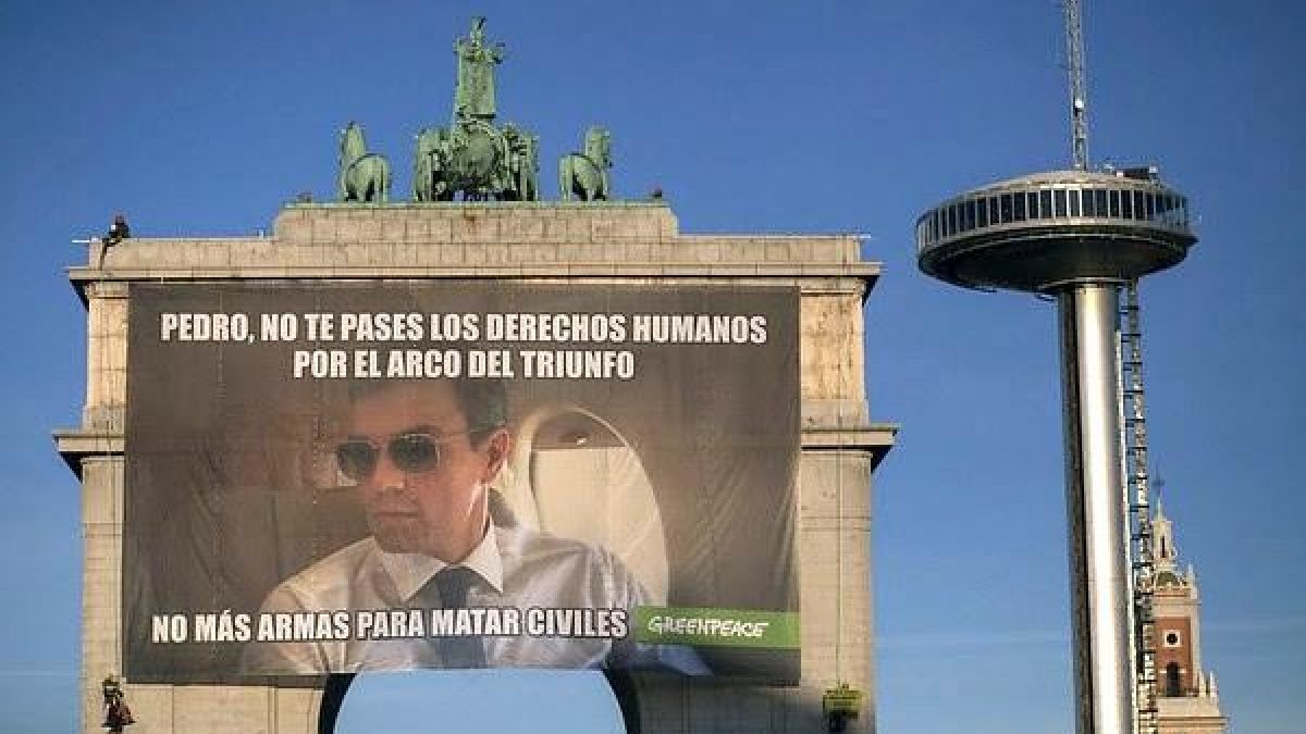 Greenpeace exigeix a Sánchez el final de la venda d’armes amb un meme gegant a l’Arc de Triomf.