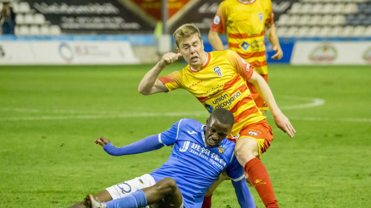 Alpha, que entró en la segunda parte, cae ante un jugador del Alcoyano en la disputa del balón.
