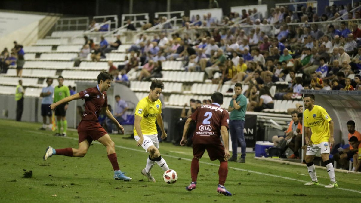Pedro Martín intenta superar con un pase la presión de dos futbolistas del Compostela.