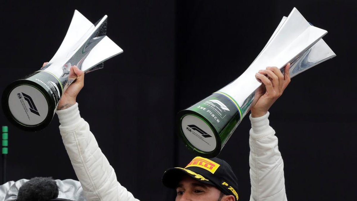 Lewis Hamilton, celebrando el triunfo en el podio con los trofeos.