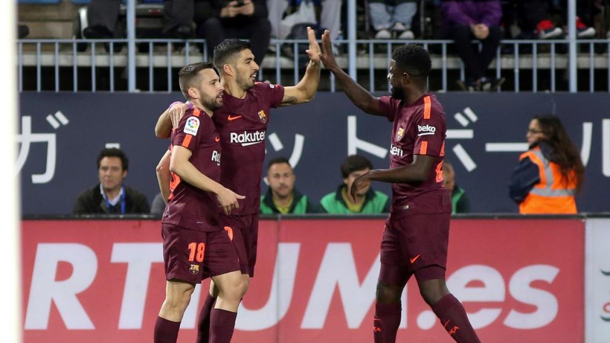 Jordi Alba i Umtiti feliciten Luis Suárez per haver marcat el primer gol de la nit, el primer que anota al conjunt malagueny.