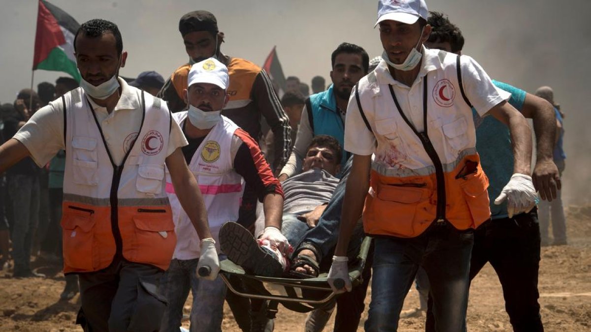 Efectivos sanitarios evacuan a un manifestante palestino herido durante las protestas en la frontera.