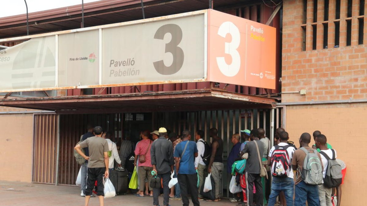 Un grupo de temporeros hace cola, el viernes por la tarde, para entrar en el centro de atención del pabellón 3 de la Fira para asearse y coger una bolsa de comida.