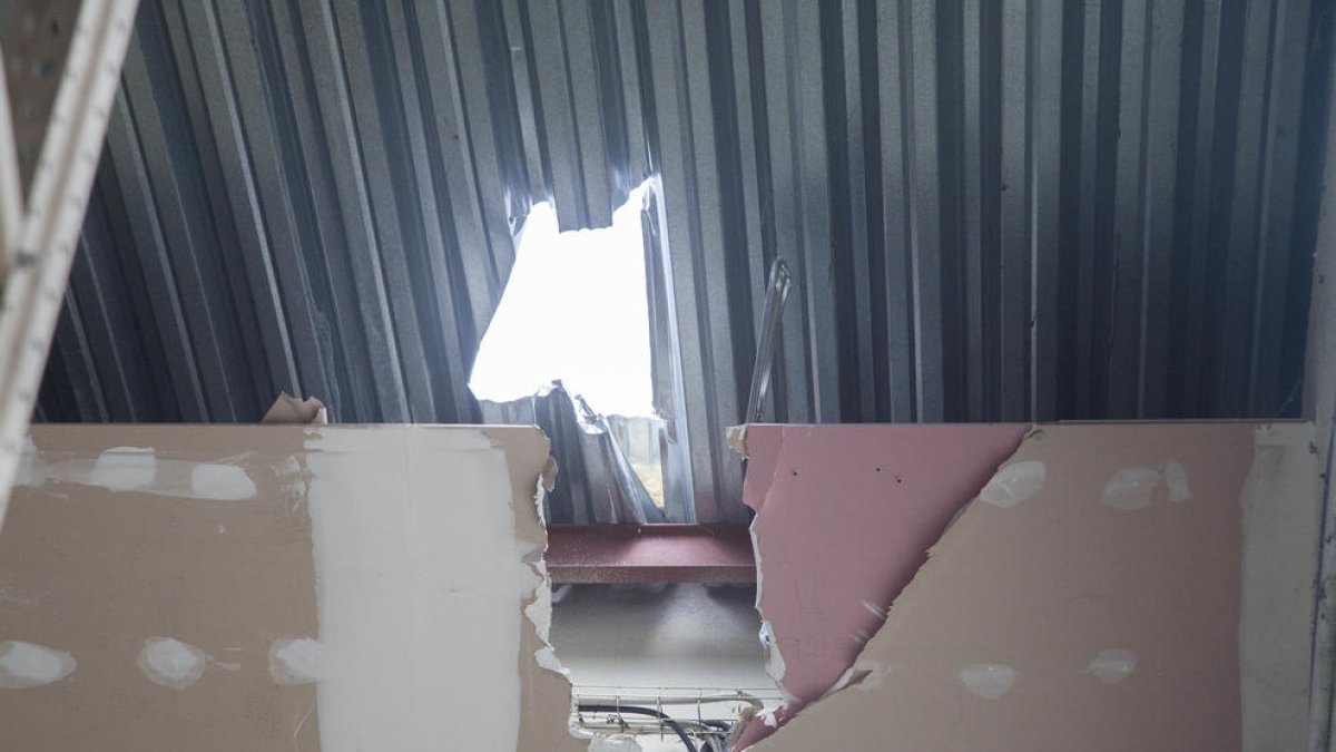 Agujero que los ladrones hicieron en el techo de Catalonia Unic (izq.) mientras que en Mainada Kids rompieron la puerta de entrada.