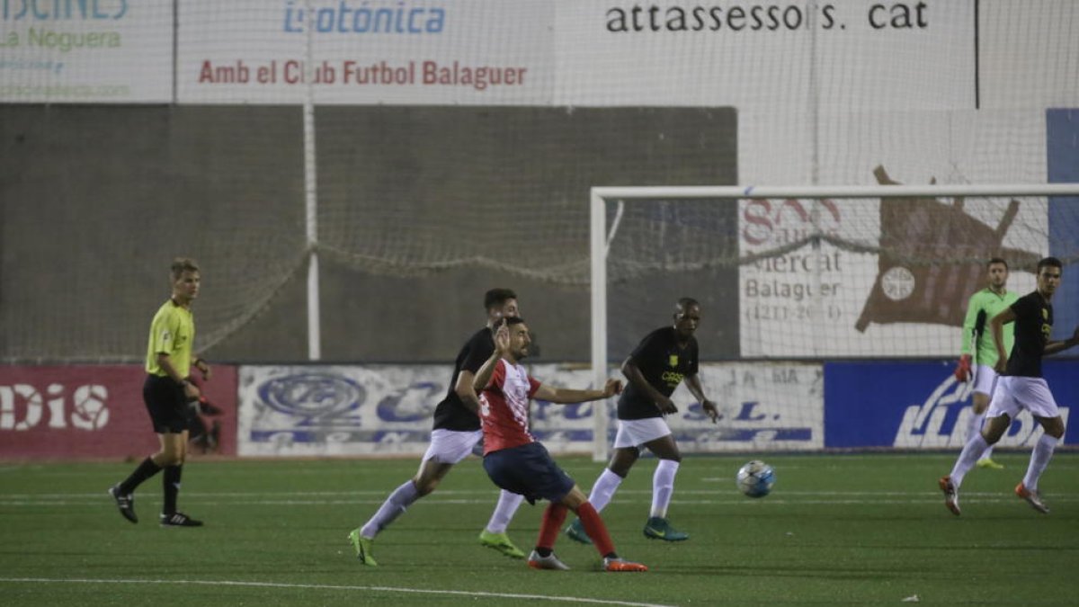 Un jugador del Balaguer desplaça la pilota davant la mirada de diversos futbolistes del Térmens.