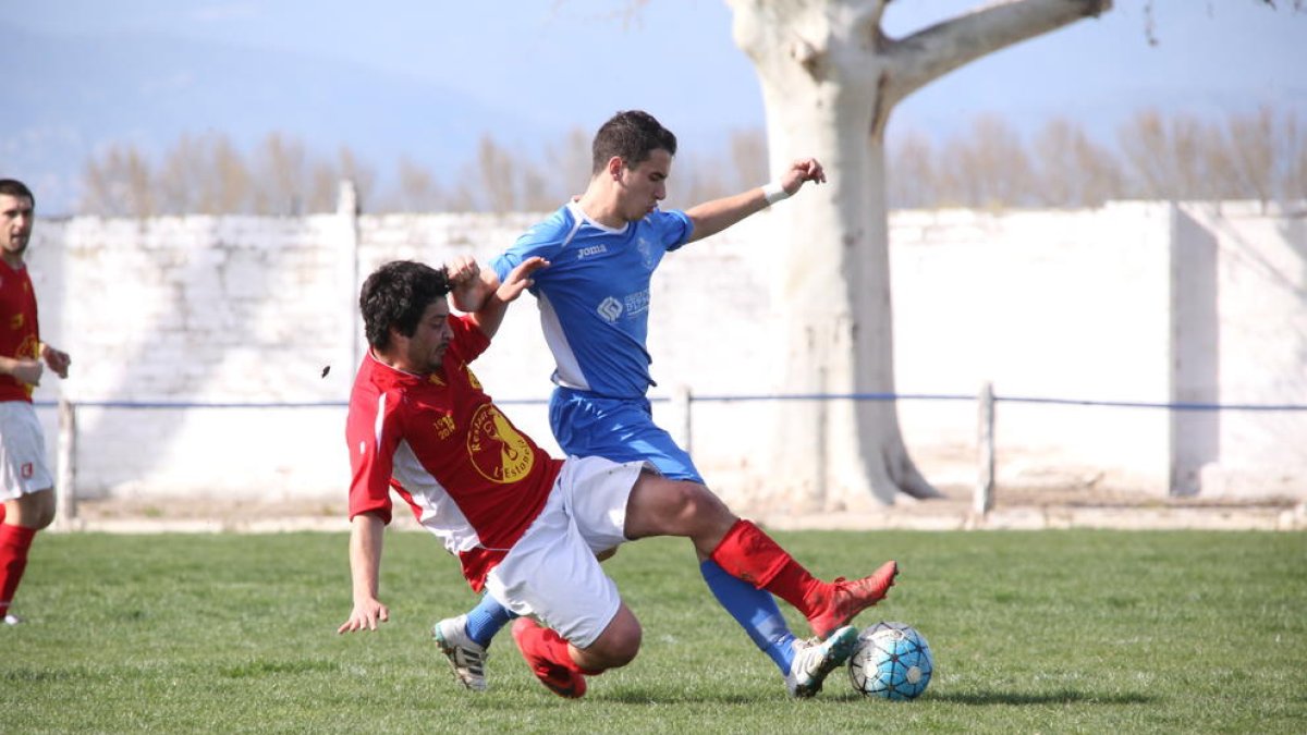 Un jugador de l’equip local i un del visitant es disputen per l’esfèric.