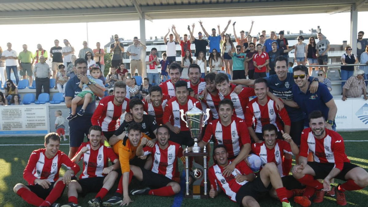 Els jugadors i el cos tècnic del Puigvertenc celebren el títol amb part de l’afició al fons.