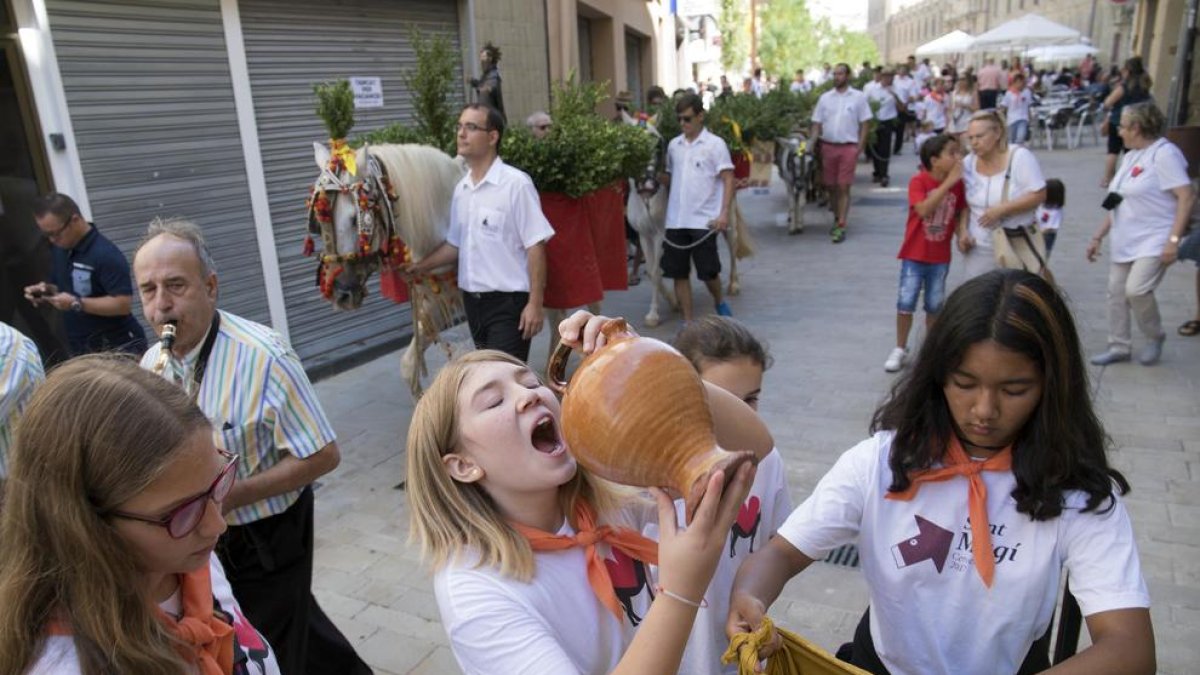 Arriba, una chica bebiendo del agua de Sant Magí en Cervera. A la derecha, la alcaldesa de Tàrrega recibiendo el cántaro conmemorativo.