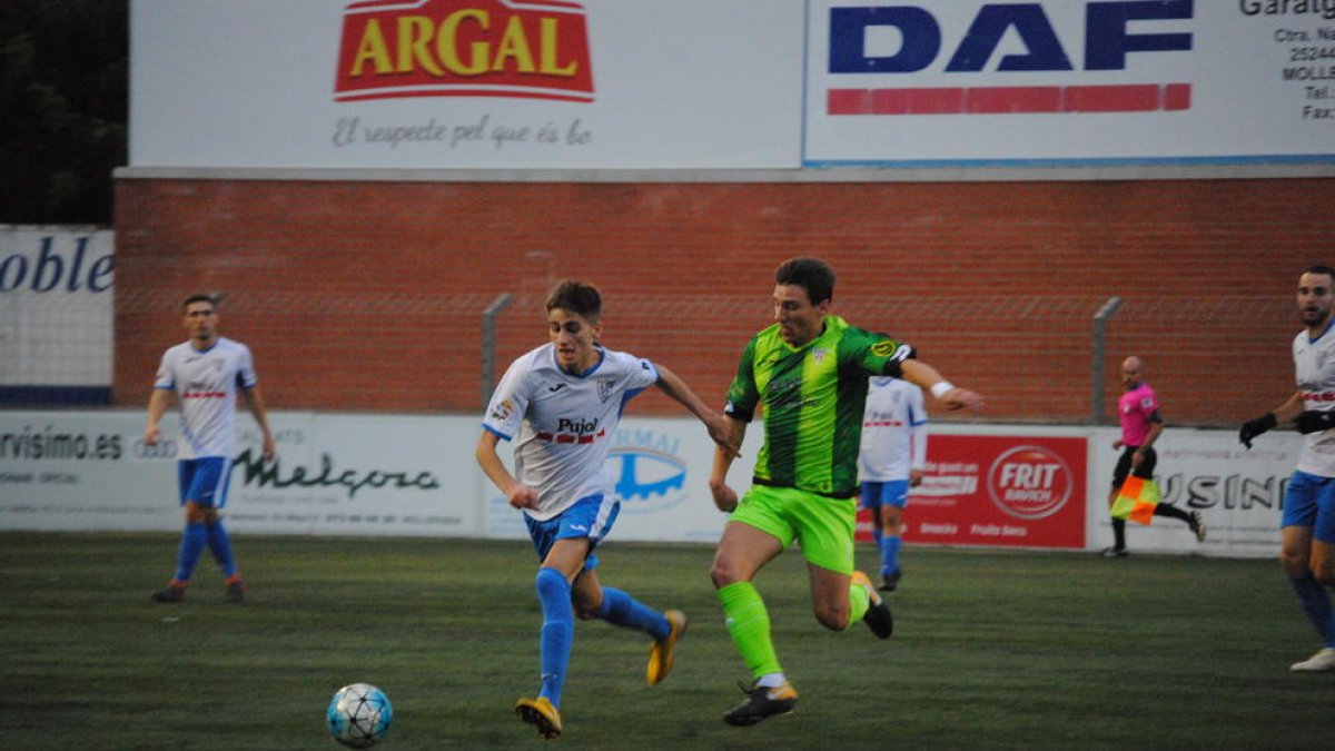 Un jugador del Mollerussa i un altre del Viladecans persegueixen la pilota durant el partit.