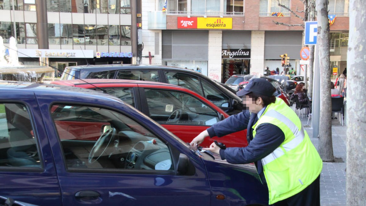 Una vigilant de zona blava imposa una multa a un vehicle.