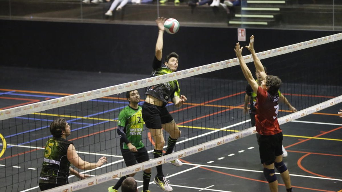 Un jugador del Balàfia intenta rematar una pilota davant el bloqueig d’un oponent del Manresa.