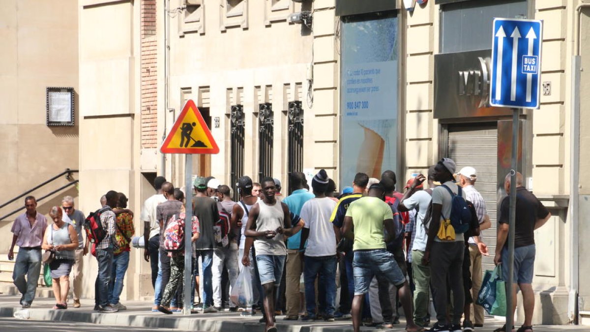 Usuarios de la Fundació Jericó, ayer, haciendo cola en la parroquia del Carme para recoger un tiques para la comida que sirven después en la calle Tallada.