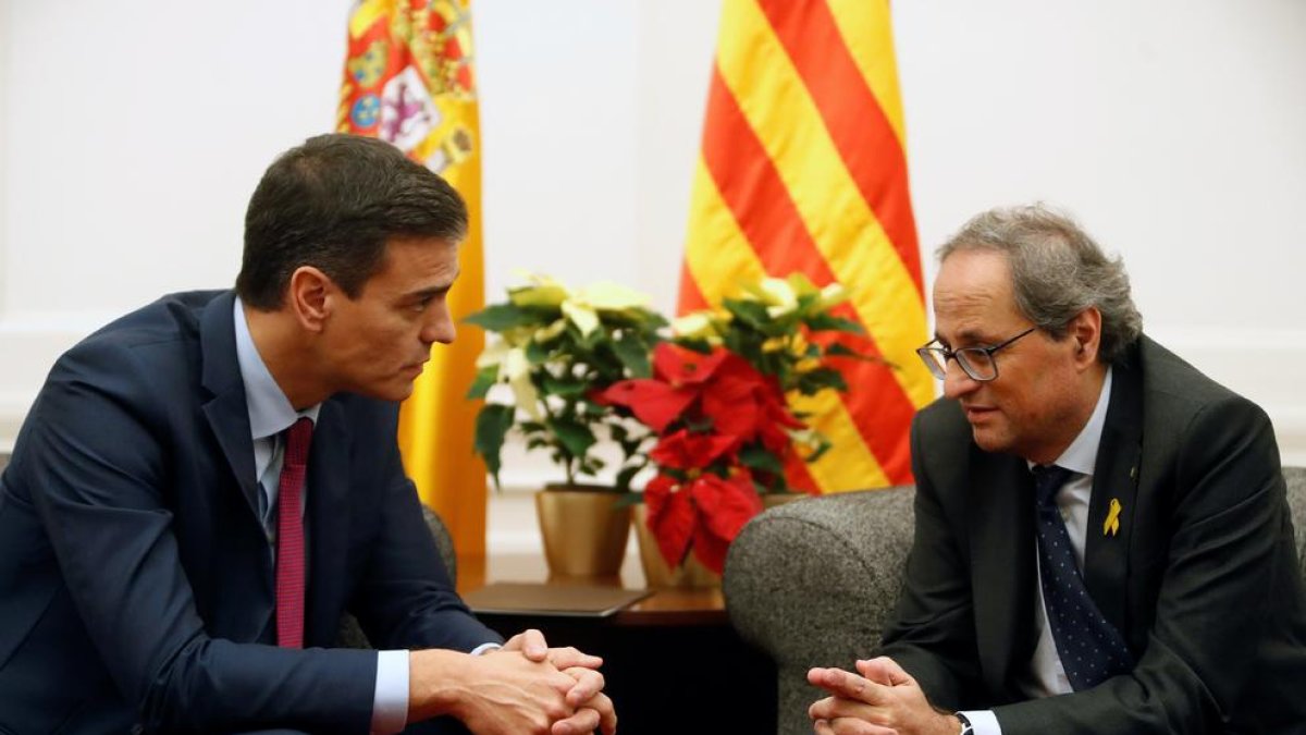 Pedro Sánchez y Quim Torra en su encuentro de ayer en Pedralbes, con las flores de la polémica en segundo plano.