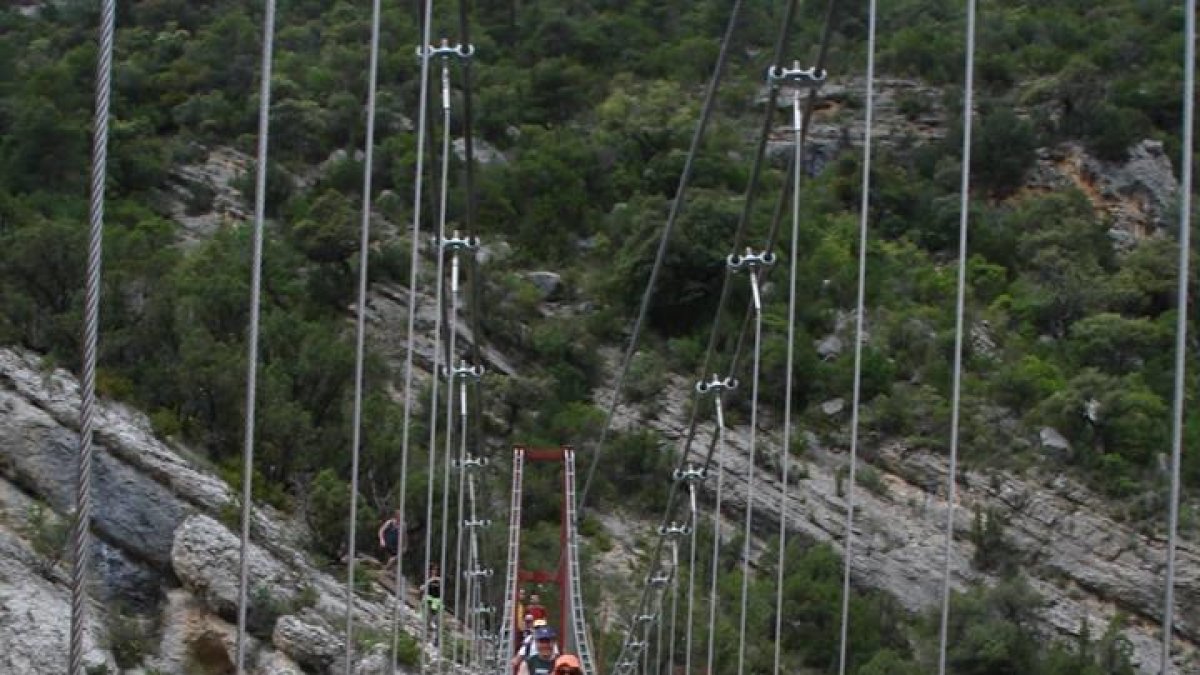 Excursionistas cruzando la pasarela de Montrebei.