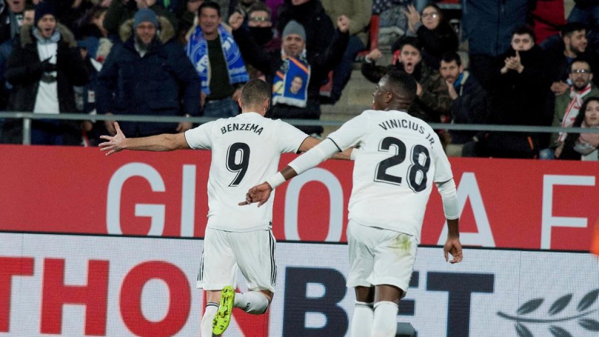 Benzema, perseguido por Vinicius, celebra uno de los dos goles que marcó ayer en Girona.
