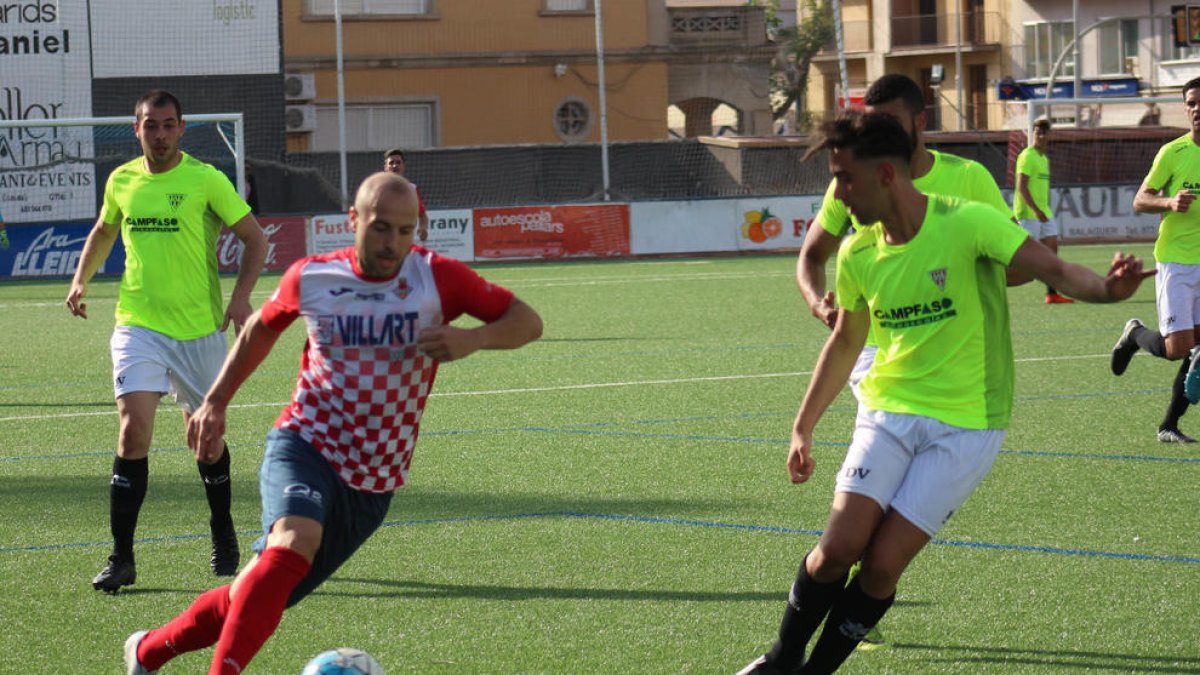 Adrià, amb la pilota controlada, encara un jugador del Viladecans, amb dos rivals més a la vora i atents a la pilota.