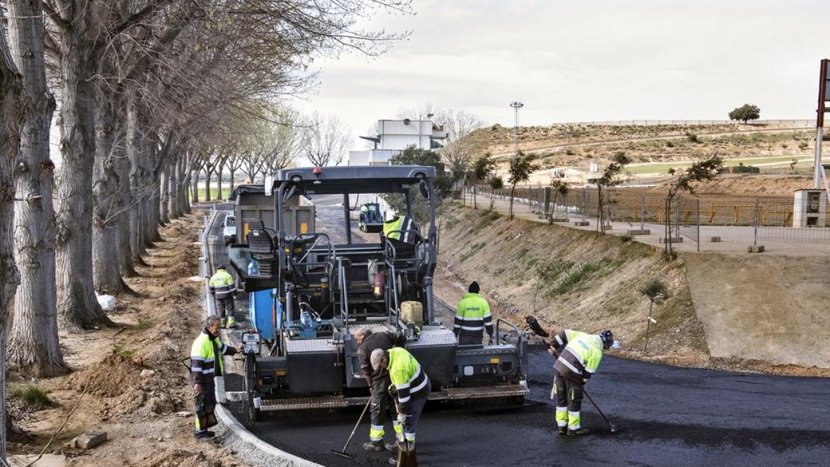 Operarios asfaltando ayer unos de los accesos situados detrás de la parrilla de salida.
