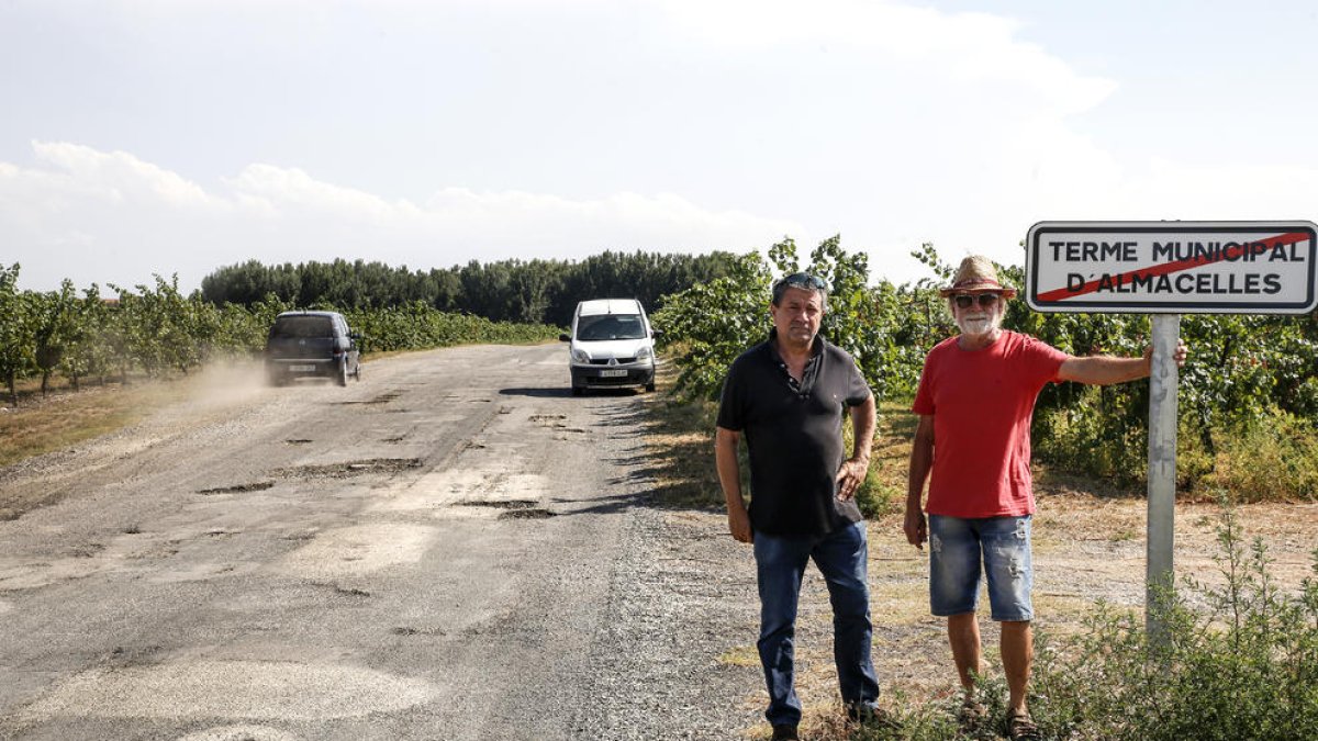 Dos vecinos ante el indicador de fin de término. Los baches pertenecen a Lleida.