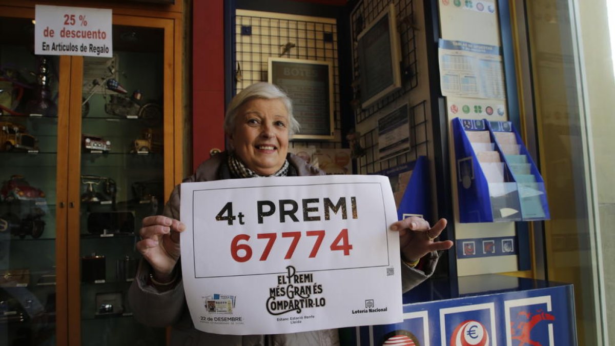La propietaria del estanco de la Estación Lleida-Pirineus, con el cartel del cuarto premio.