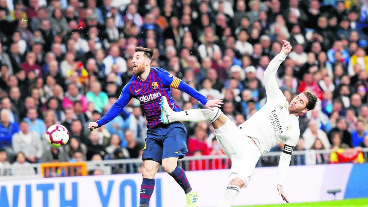 Messi intenta llevarse el balón ante Ramos que pretende frenarlo.