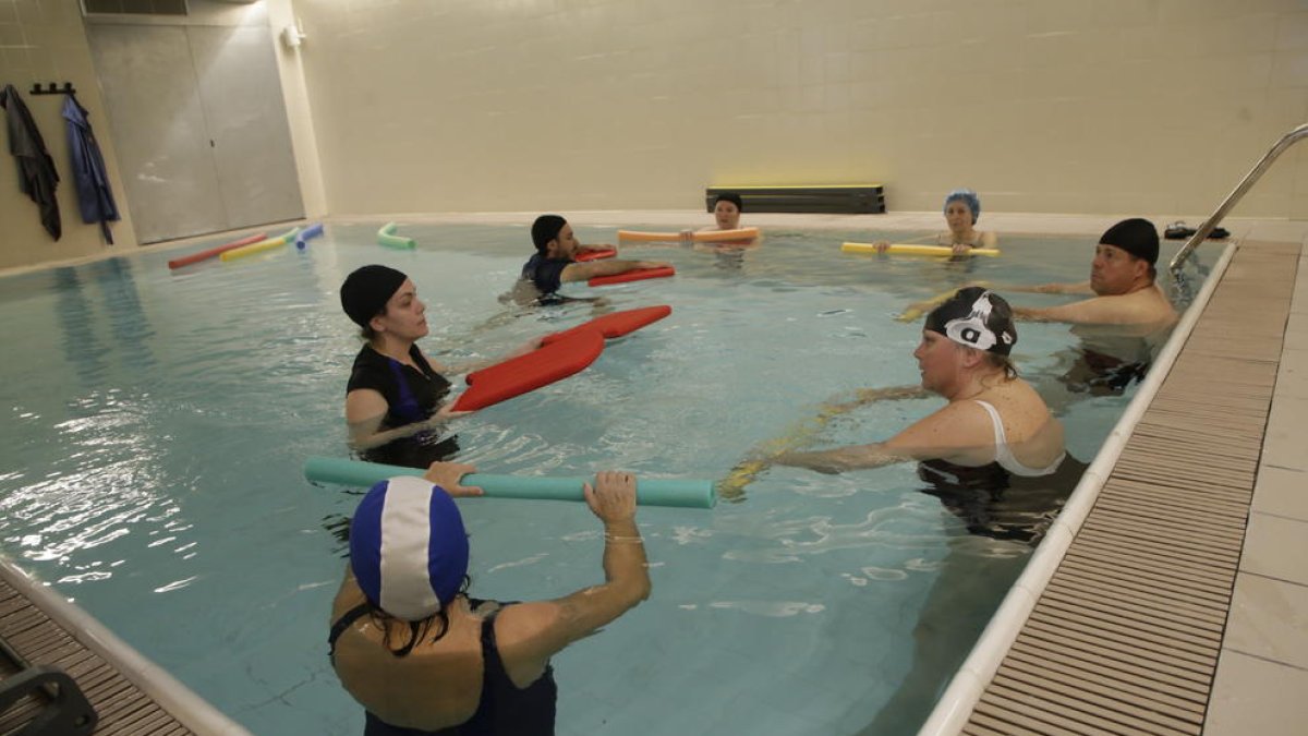 A l’esquerra, pacients fent ahir exercicis de rehabilitació i, a la dreta, una grua que permetrà ajudar usuaris a entrar a la piscina.