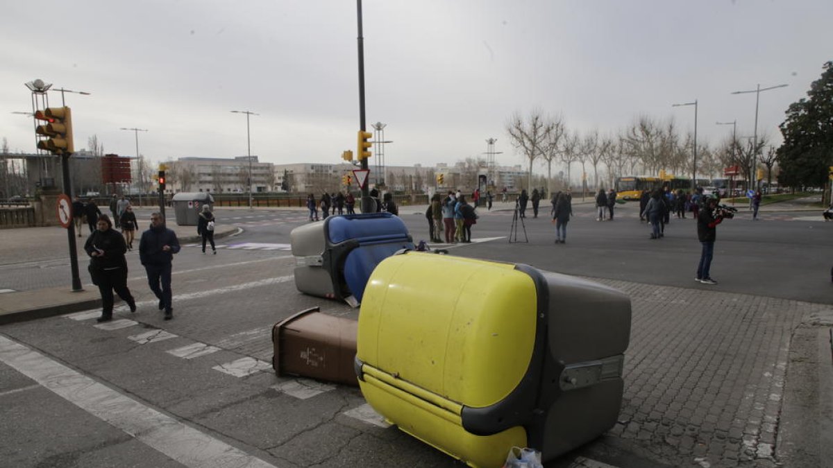 Contenidors bolcats i, al fons, autobusos aturats.