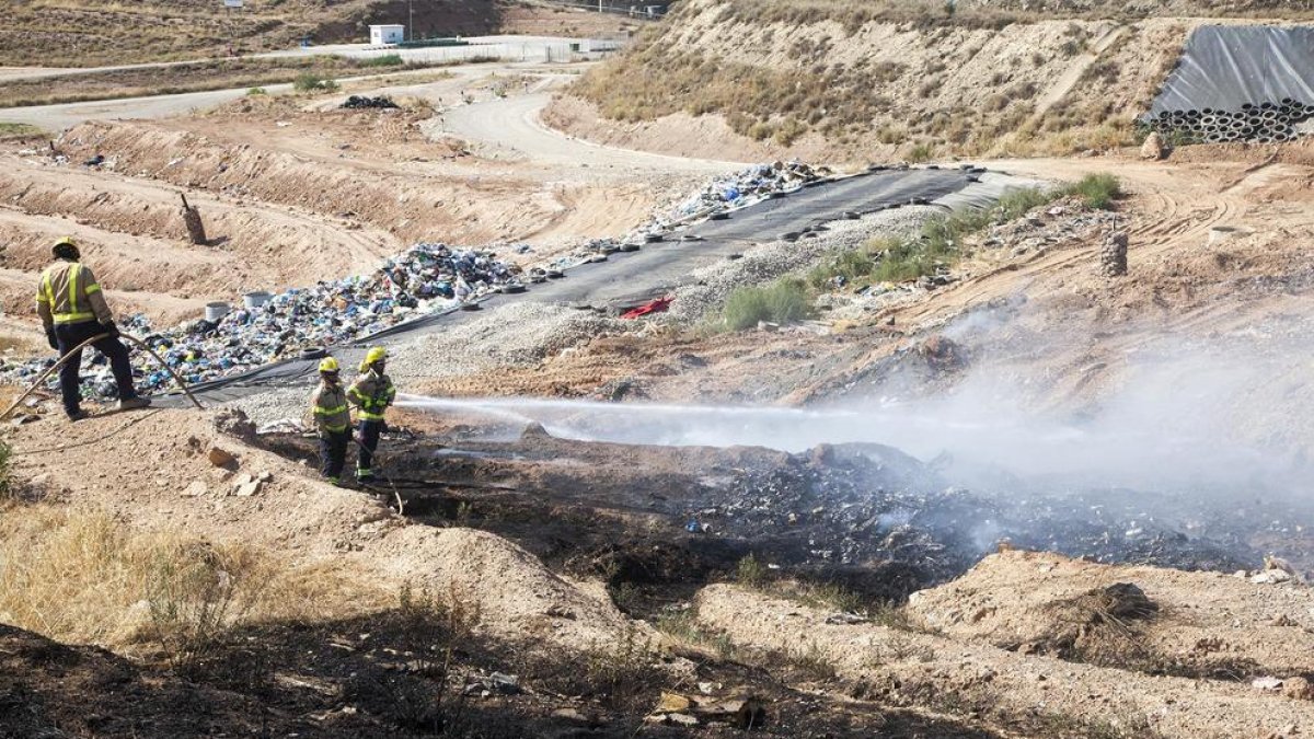 Bomberos remojaban ayer los residuos del vertedero de Tàrrega para evitar que las llamas se avivaran.