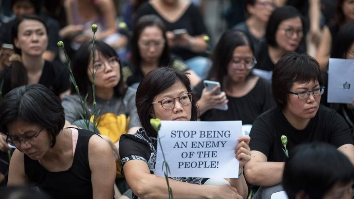 Una hongkonguesa sosté una pancarta en la qual es llegeix “Deixeu de ser un enemic del poble”.