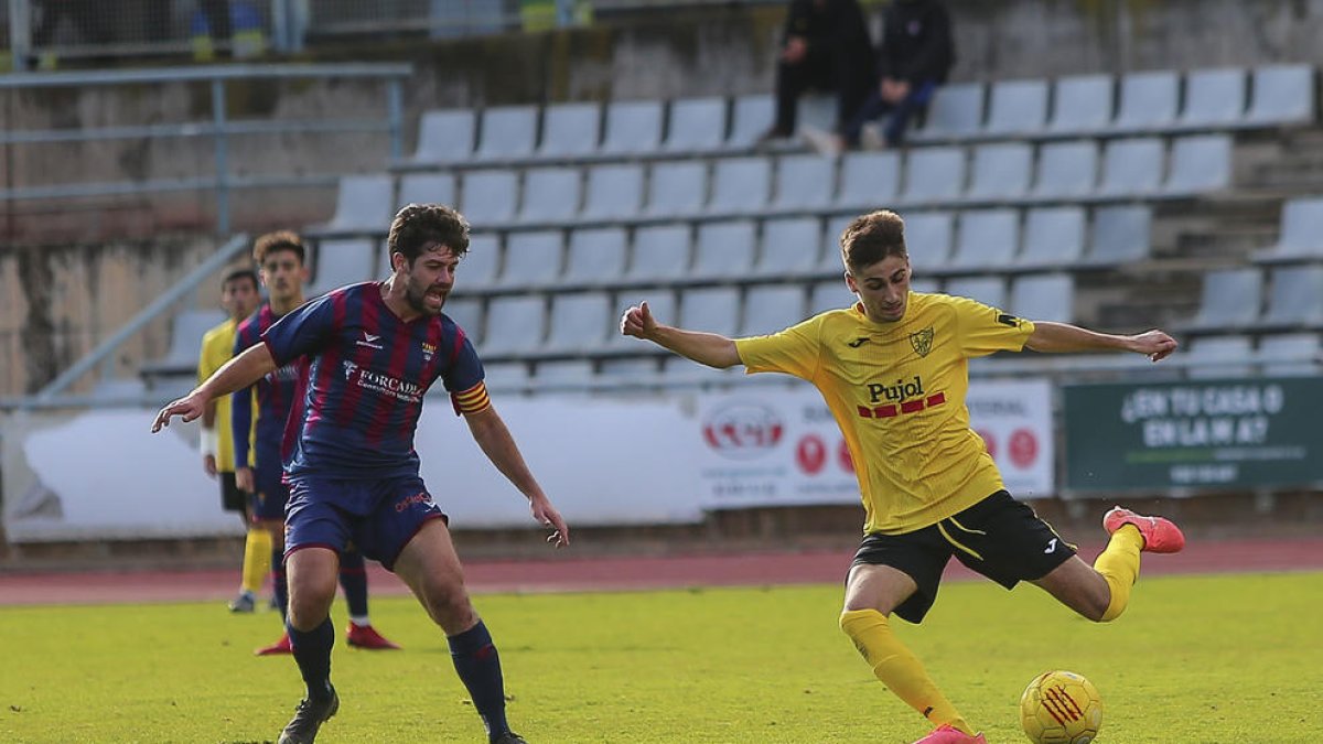 Un jugador del Mollerussa es disposa a centrar la pilota davant la presència del capità del Gavà en una de la jugades del partit d’ahir.