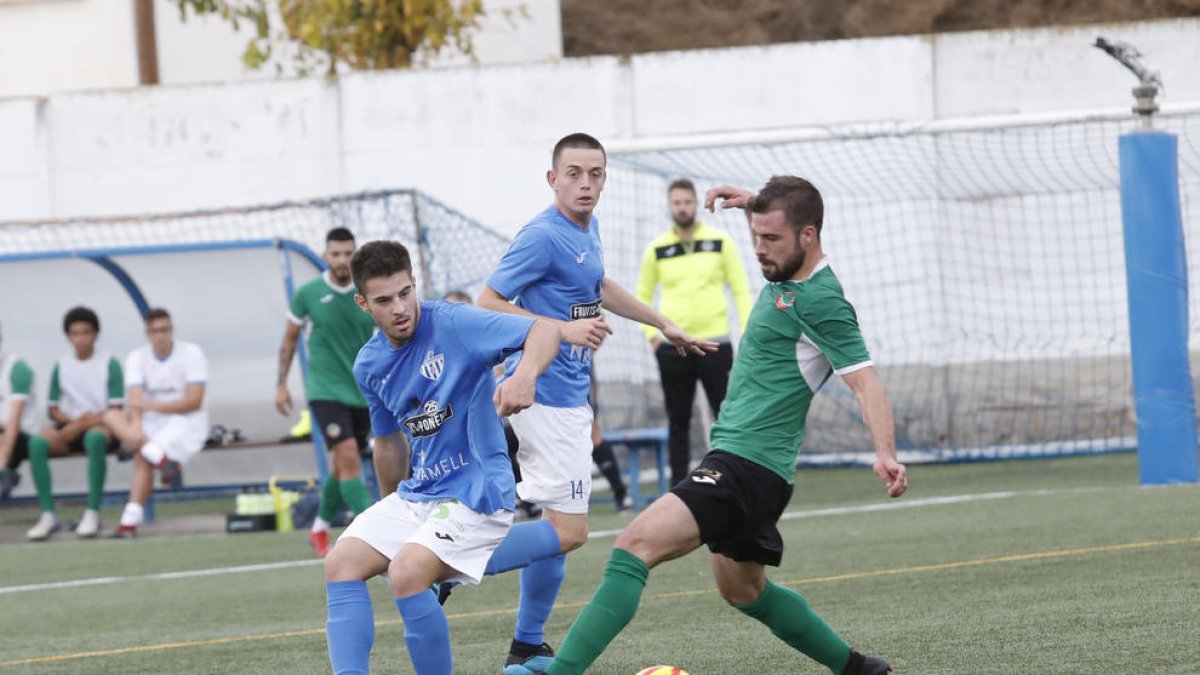 Un jugador de l’Alcarràs prova de desplaçar la pilota assetjat per un altre de l’Ascó.
