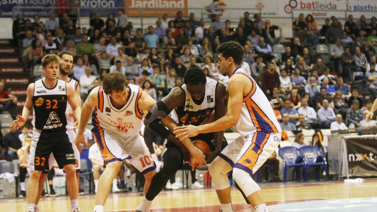 Ablaye Mbaye, pivot de l’Actel Lleida, lluita per una pilota amb Urko Otegui i Bryce Pressley, dos dels jugadors més destacats del Palència.